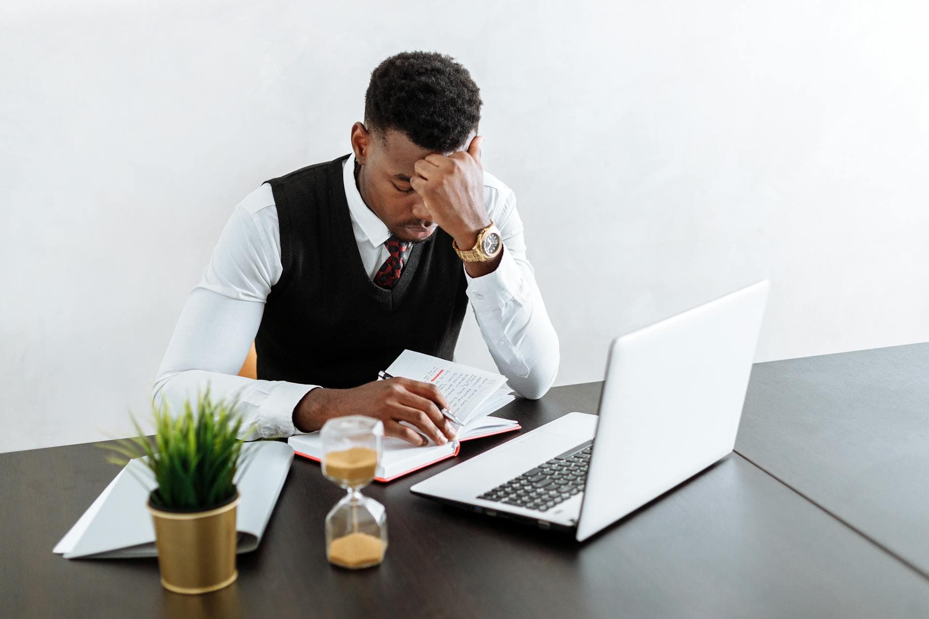 Businessman in office focusing on work with laptop and hourglass.